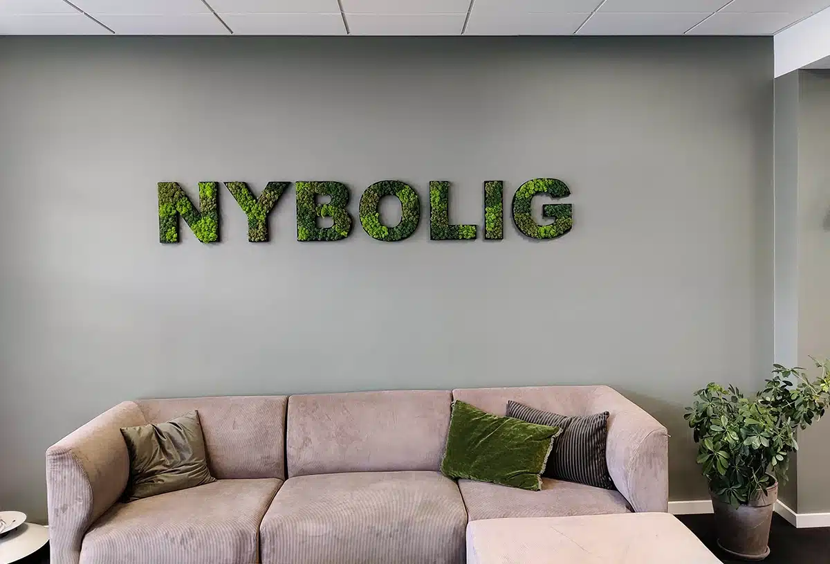 Birou modern cu canapea și artă de perete cu plante.